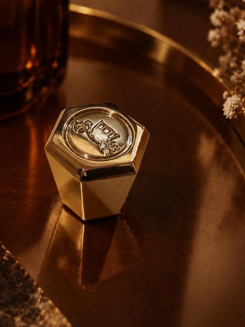 The hexagonal cap in close-up, its central button carrying Savile Row's stagecoach motif