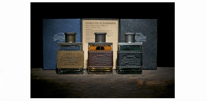 Superdry fragrance bottles lit on a dark display plinth